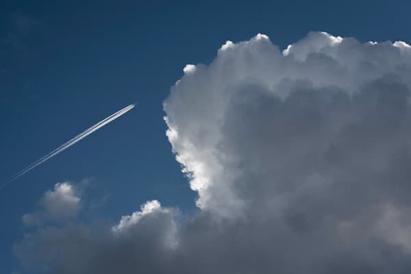 Blauer Himmel mit Cummuluswolken und Flugzeug mit Kondenzstreifen